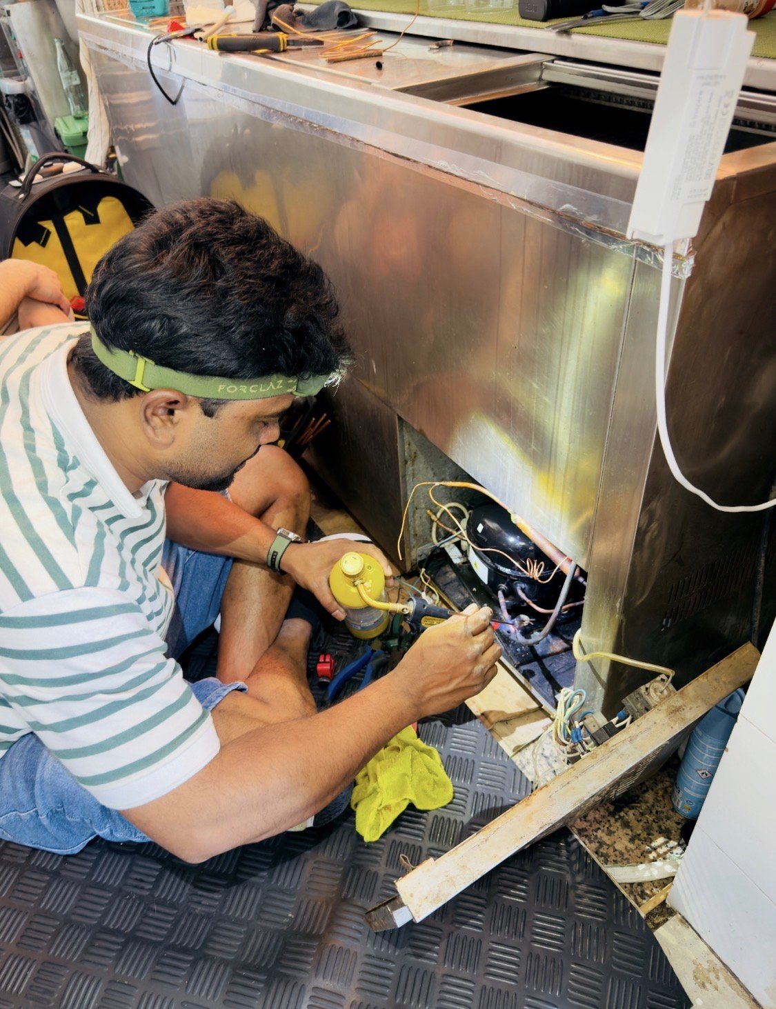 Técnico sustituyendo el compresor de una vitrina refrigerada comercial en Barcelona